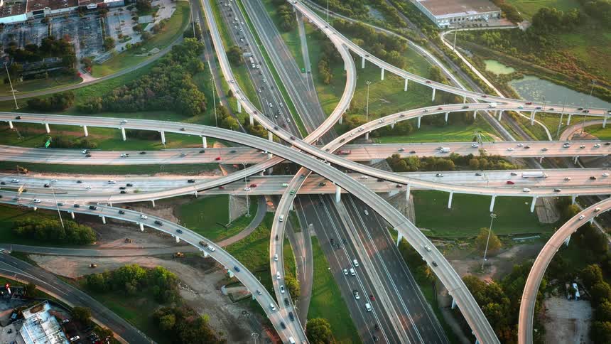 Aerial view of cards driving over a highway interchange at evening