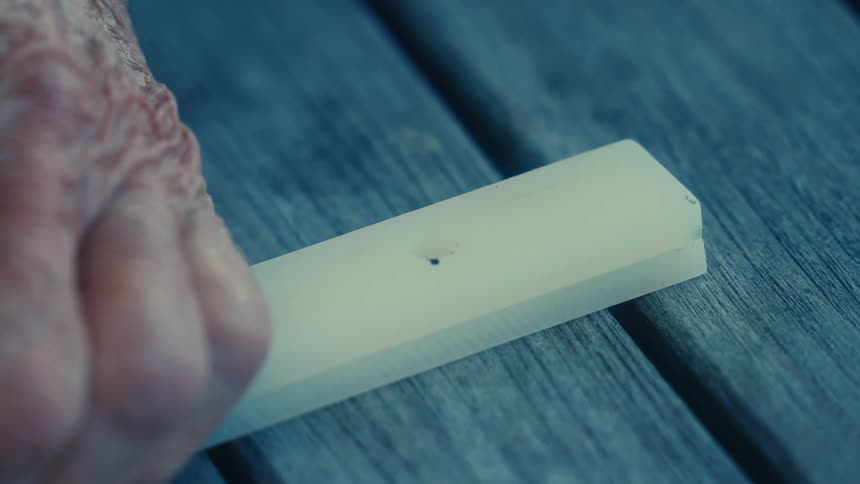 A person marking two strips of material with a permanent marker