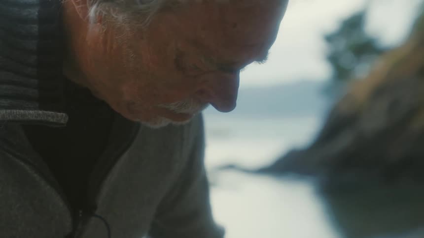 Close up of the face of an elderly man unpacking near a lake at morning
