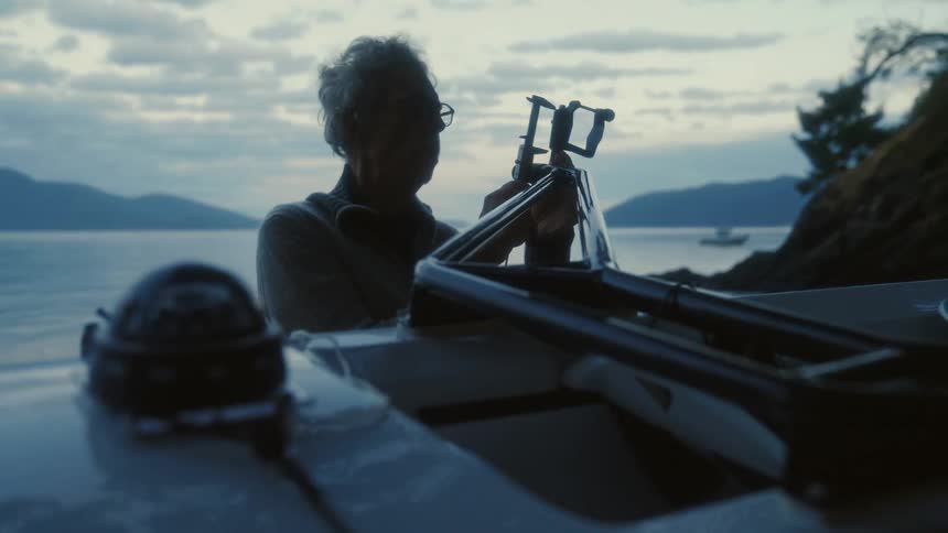 A man standing near the water and a boat using a caliper tool to measure