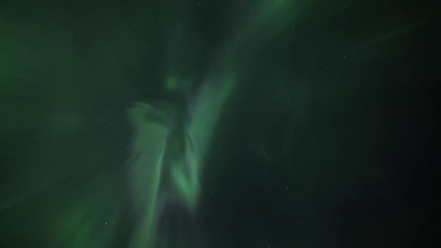The green glow of the northern lights shine as the aurora borealis moves and stars twinkle