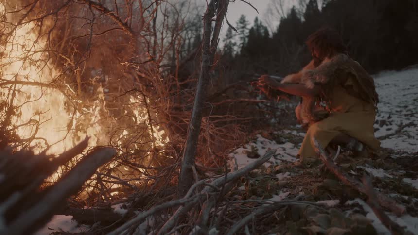 A man warms his hands by a large fire
