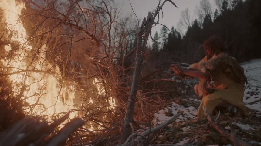 A man warms his hands near a fire