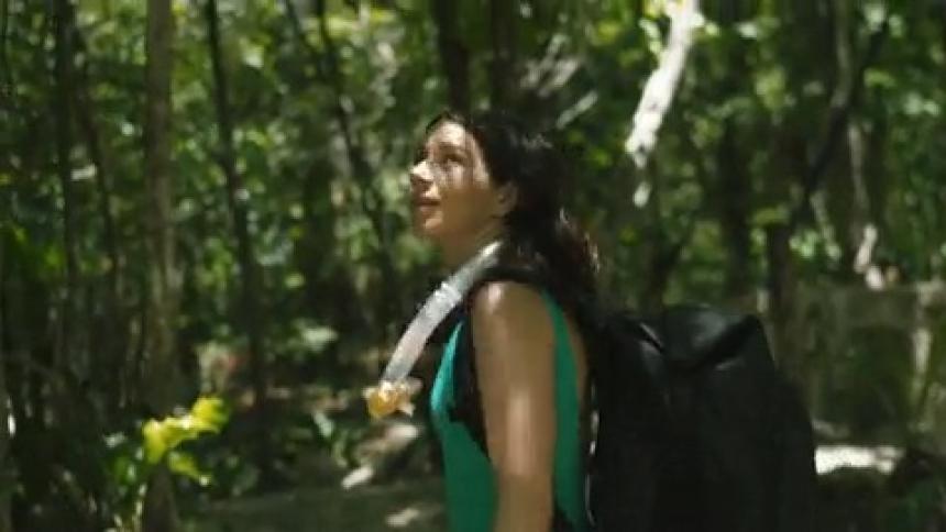 A woman wearing diving gear hikes through the rain forest
