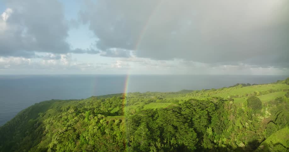 A rainbow touches down over a cliff along the coast
