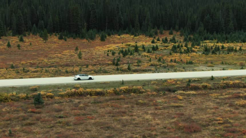 An aerial view of a car driving down a road