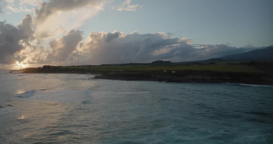 Aerial view of shoreline and highway next to ocean at sunset