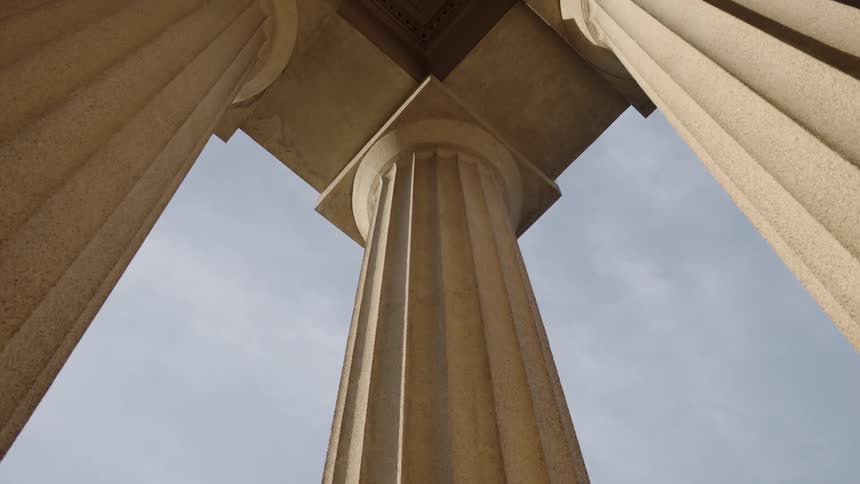 Tall marble columns hold up the corner of a capital