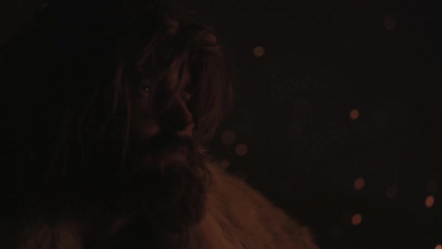 A man gazing into the distance as sparks float behind him in the night sky