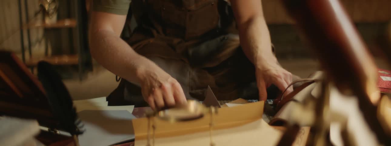 Leather craftsman cutting paper patterns with small scissors in his workshop
