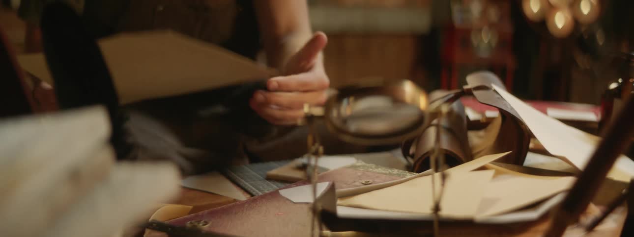 Person crafts using paper near magnifying glass