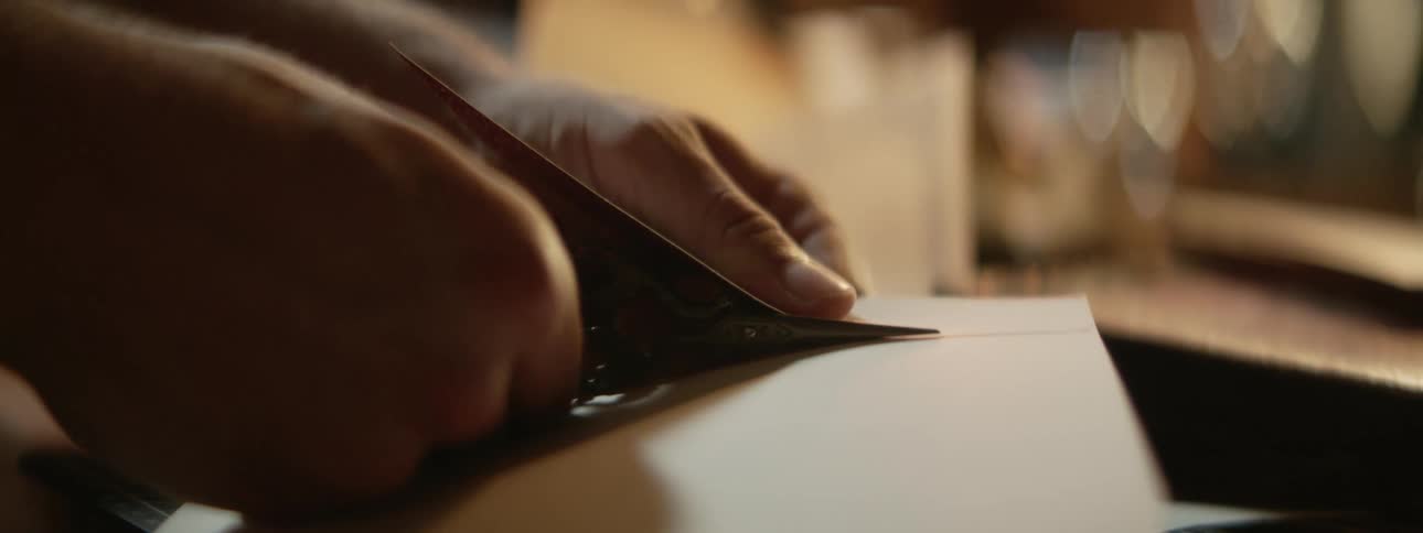 Person uses scissors to cut strip off sheet of paper