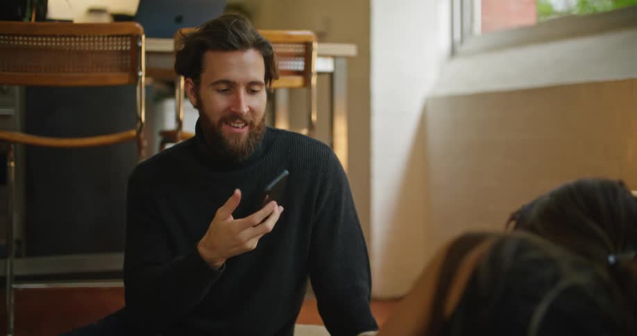 While sitting on the floor together a man shows smartphone screen to a woman