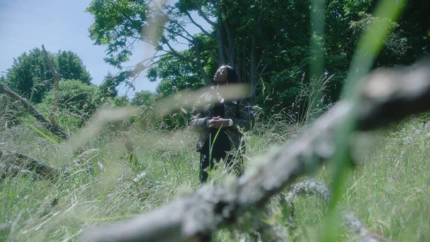 A woman stands in the tall grass