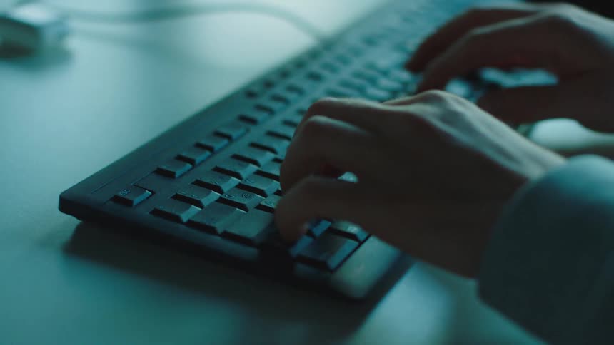 A person is typing on the black keyboard