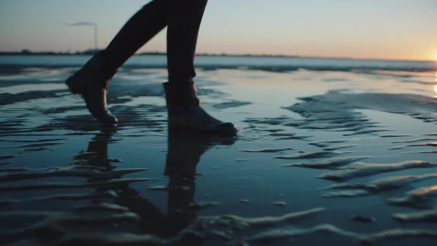 A man walks through slushy water along the coast