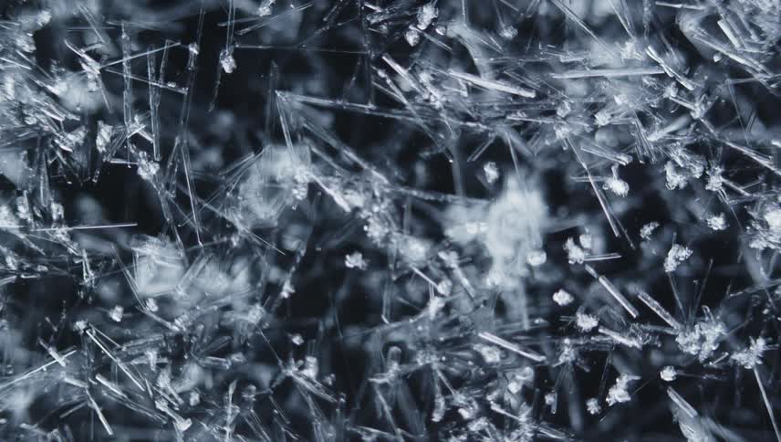Ice crystals form as translucent shards against a dark background