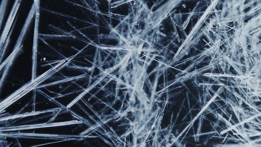 White crystal shards form thickly on dark background