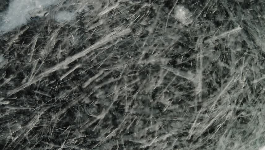 Translucent icy shards form on dark surface