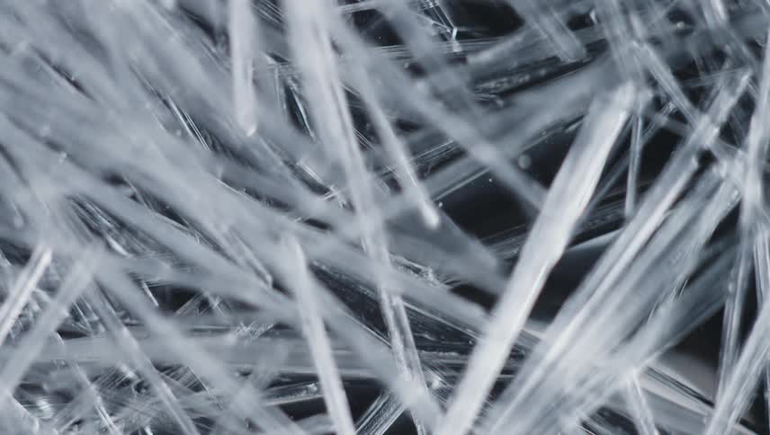 Thin crystalline splinters grow and obscure black background