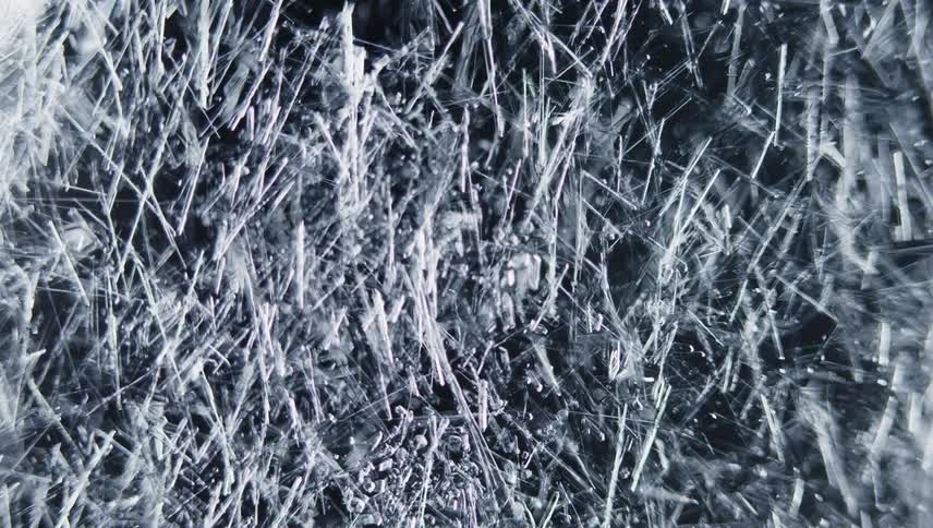 Translucent crystalline shards grow into dense carpet over black background