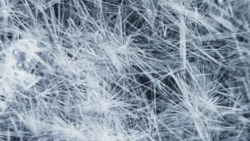 Time lapse of white thin ice crystals forming against a black background