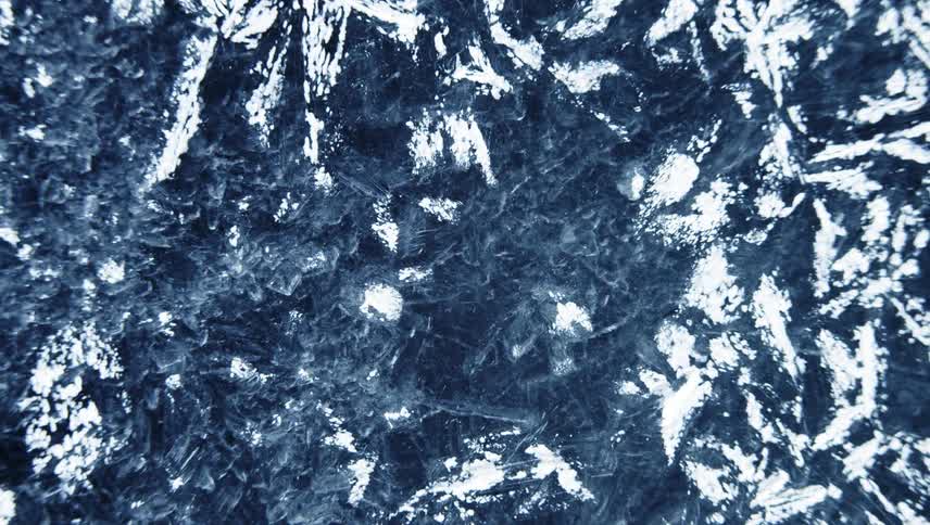 Ice crystals are being formed in water and are shown slowly evolving and highly magnified