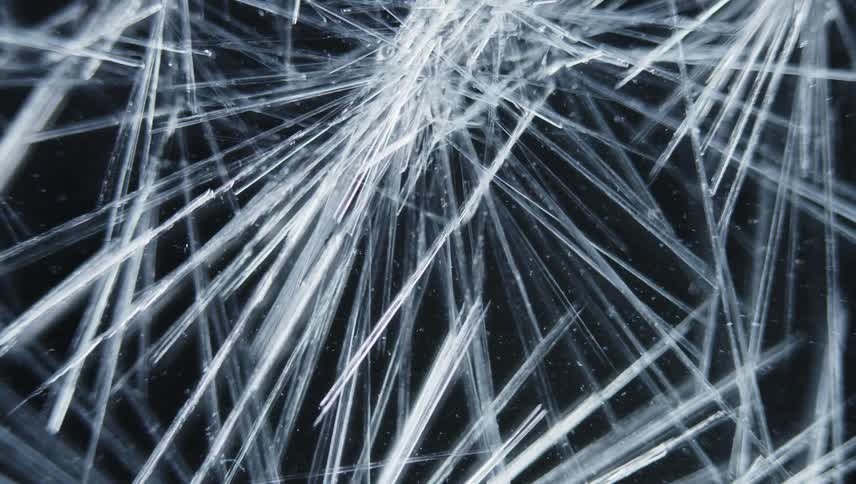 Ice cracks slowly and is highly magnified on a black background