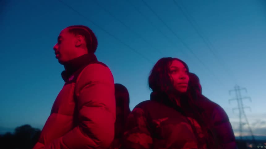 Group of models standing under a red light on a town street at evening looking at the camera