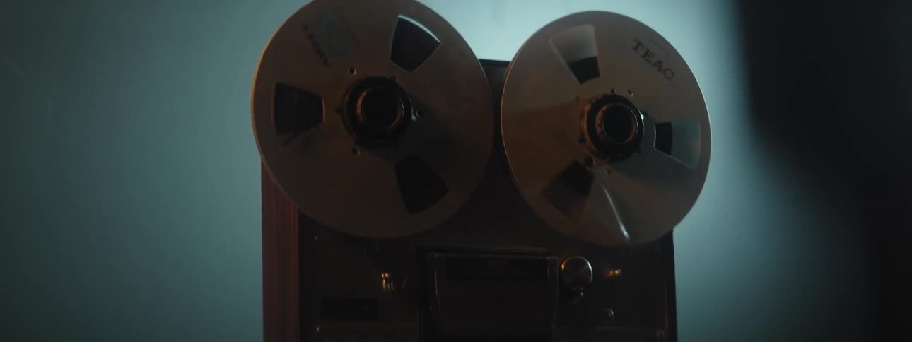 The wheels of an old reel to reel movie player turns as it plays