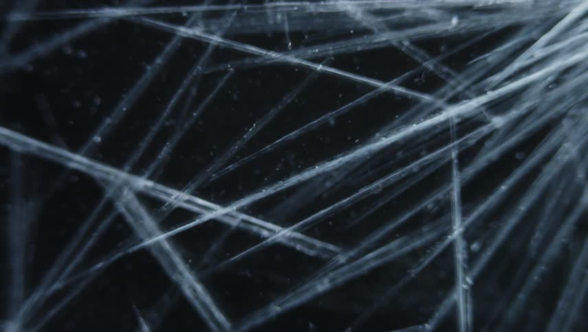 Twisting close up of thing ice crystals forming in front of a black background