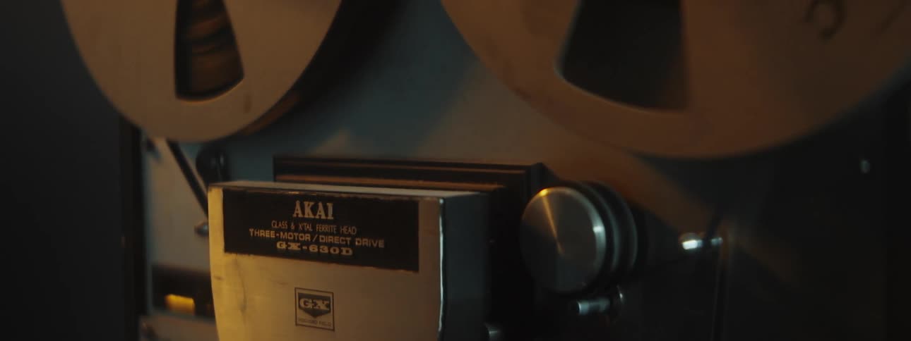 Close up of a vintage tape recorder spinning inside a dimly lit room