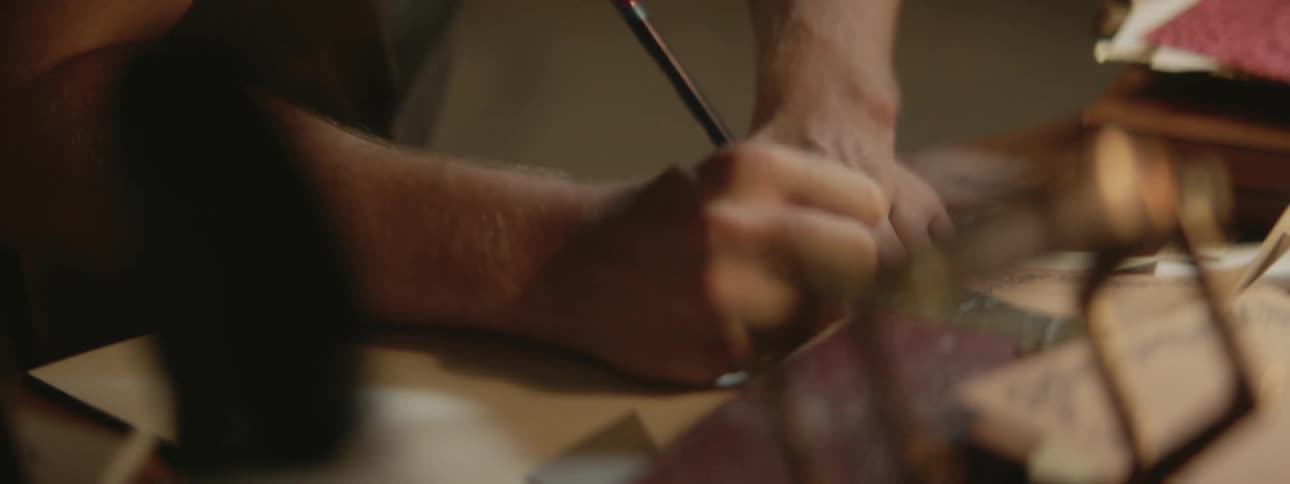 Close up of the hands of a man drawing with a ruler and a pencil over paper on a desk