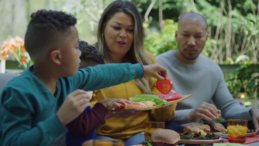 Family eats hamburgers on patio