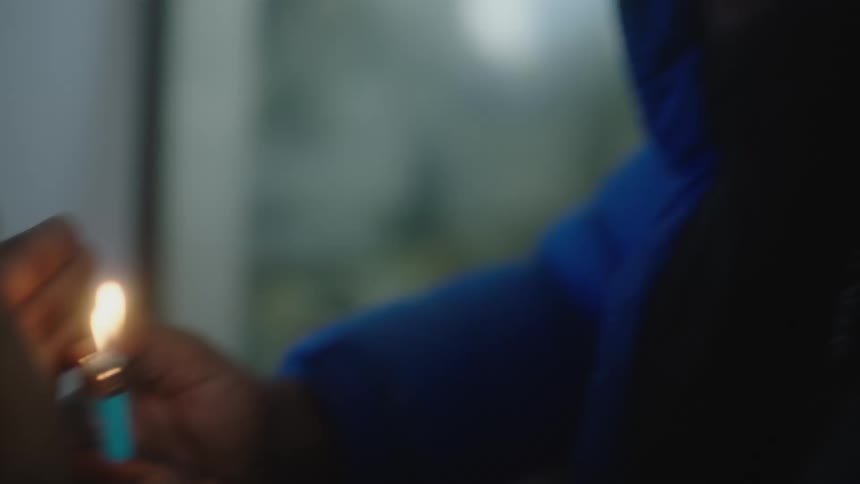 Young man lights a lighter on a room
