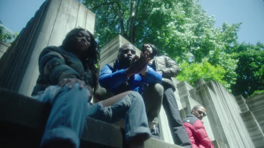 Group of models wearing thick jackets modeling for the camera near a concrete structure on a park