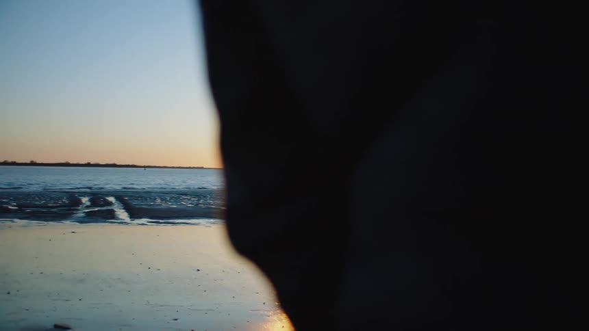 A person stands on the beach and watches waves crash onto the shore