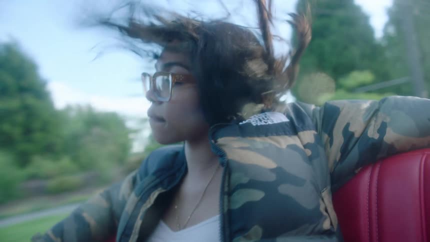 Young beautiful woman wearing a thick jacket sitting on the back seat of a convertible driving in the morning