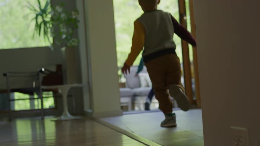 Young kids running from the living room to the porch to join their parents eating outdoors