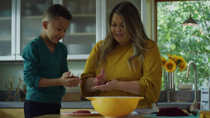 Mother shows son how to make hamburger patties in the kitchen