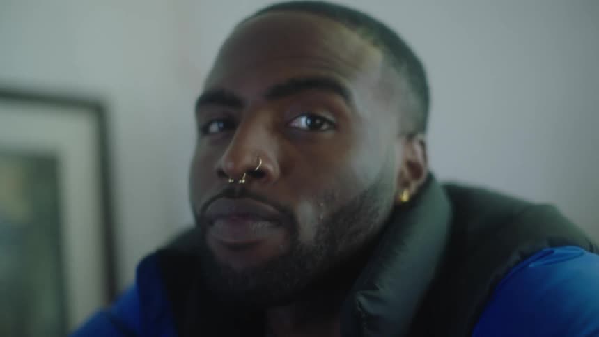 Close up of the face of a young handsome man wearing earring and nose hooks looking at the camera