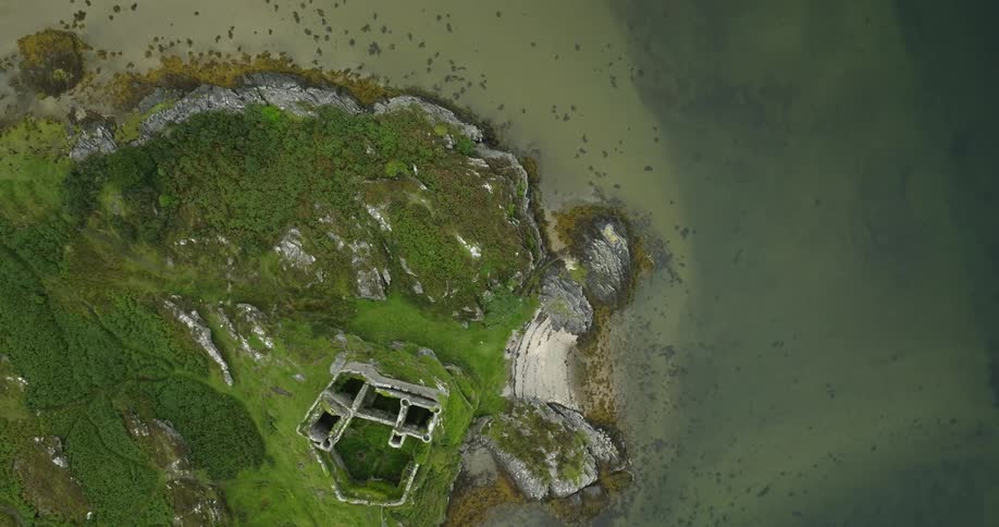 Top down aerial view of an abandoned castle tower on the coast of a lake