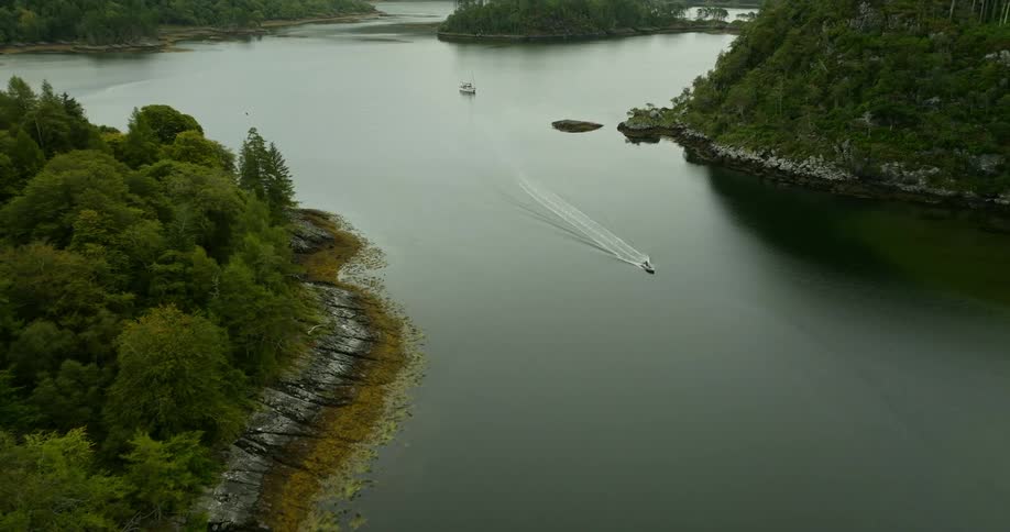 Aerial view of a small boat sailing on the calm surface of a river on the mountains
