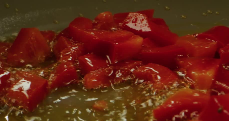 Peppers are shown cooking in a skillet and being moved back and forth slowly
