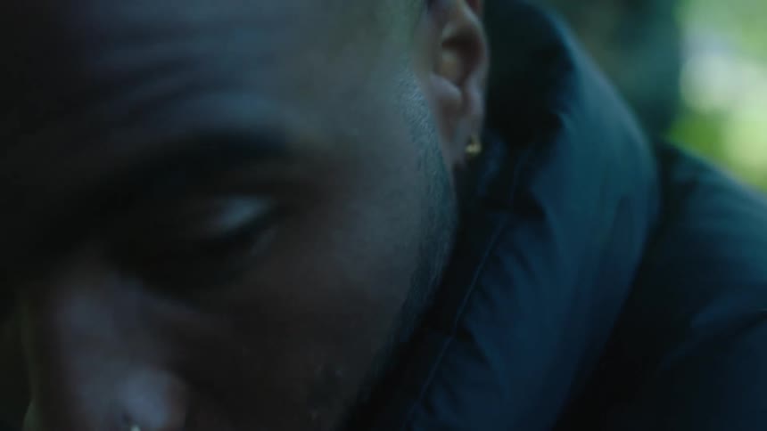 Man outdoors wearing dark coat turns his head