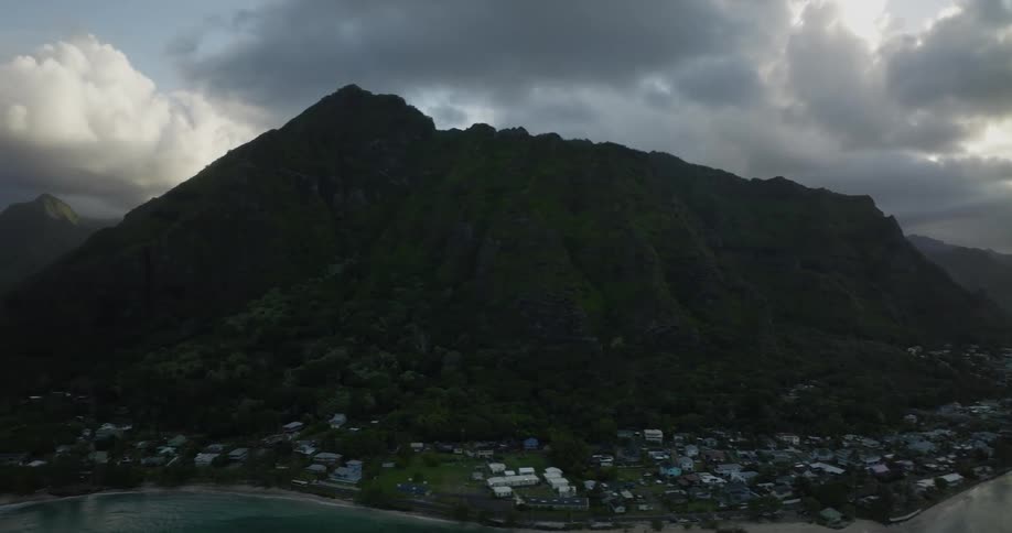 Aerial view of a small coastal town on the slopes of a mountain next to the ocean on an island at morning