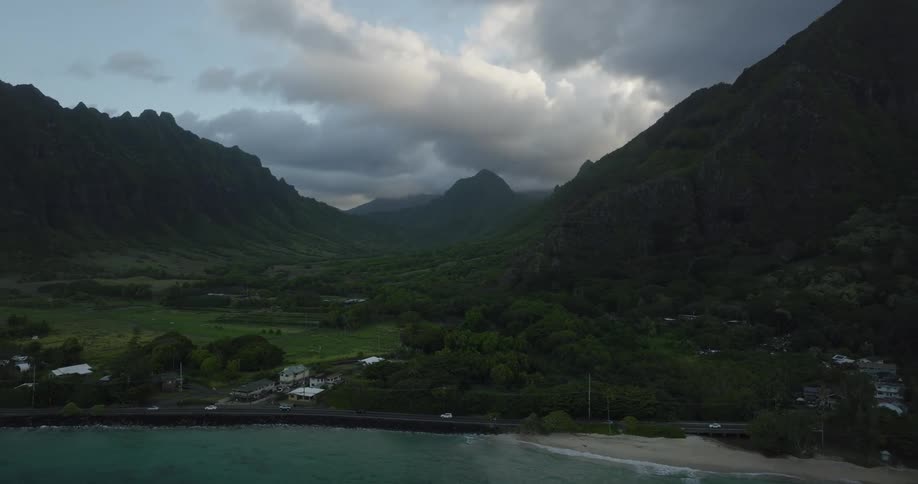 Traffic drives along a coastal highway past a neighborhood below tall cliffs