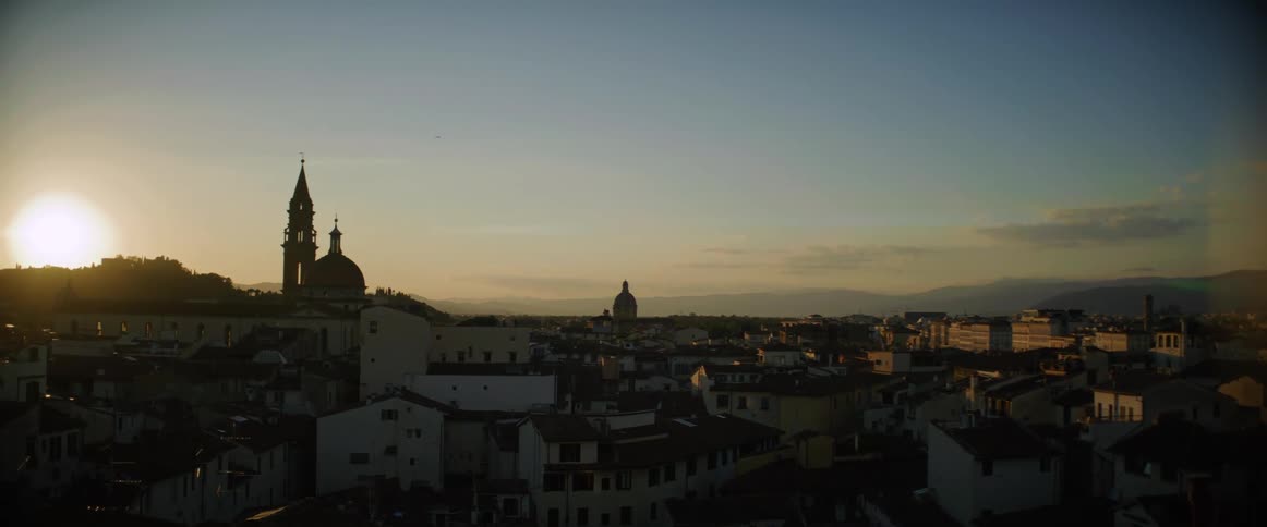 A clock tower sits above a dense neighborhood
