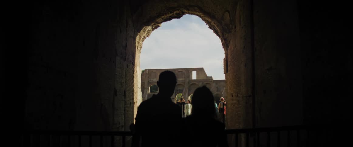 People stand in a doorway of a stone building and watch people outside