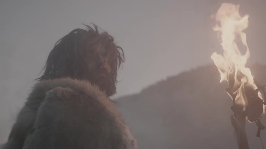 A man holding a torch looks to his right